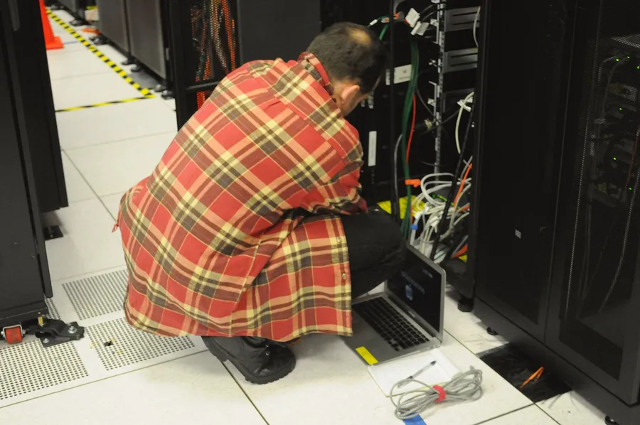 Un técnico revisando un armario de servidores con el portátil
